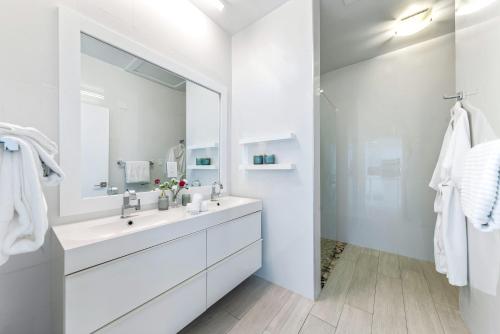 a white bathroom with a large mirror and a sink at Lighthouse Point Residences in West Bay