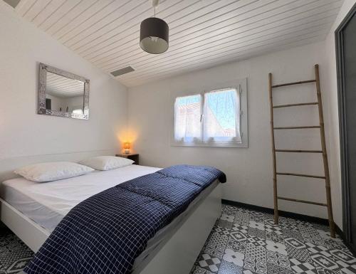 a bedroom with a bed with a blue blanket at 4HTAMA5-Charmante maisonnette avec terrasse in Le Barcarès