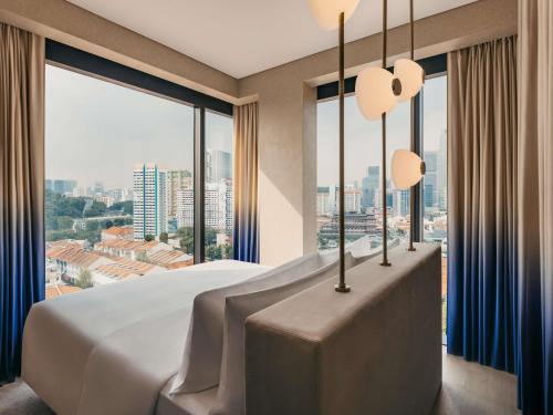a bedroom with a large bed and large windows at Mondrian Singapore Duxton in Singapore