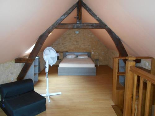 a attic bedroom with a bed and a chair at gite a la ferme in Milhac