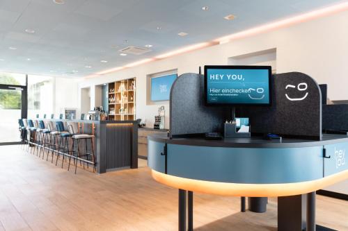a waiting room with a counter with a tv and chairs at Hey Lou Hotel Friedrichshafen in Friedrichshafen