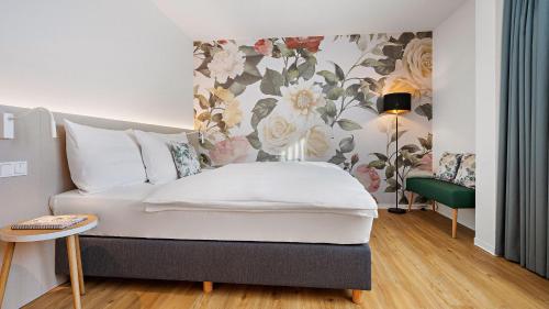 a living room with a white couch and a floral wall at Hey Lou Hotel Karlsruhe Messe in Karlsruhe