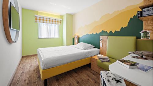 a small room with a bed and a desk with a bed sqor at Hey Lou Hotel Piding in Piding