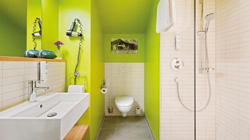 a bathroom with green walls and a toilet and a sink at Hey Lou Hotel Piding in Piding
