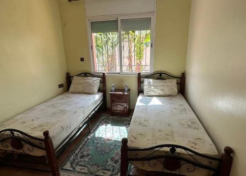 two beds sitting in a room with a window at Beautiful Duplex in secure residence with 2 pools in Sidi Bouzid
