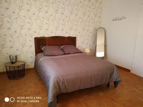 a bedroom with a large bed with purple pillows at Gîte Saint Gorgon in Euville