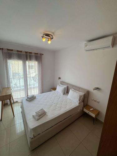a bedroom with a bed with white sheets and a window at Paleochora Apartments in Palaiochora