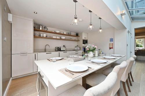 a white kitchen with a long table and chairs at Hydrangea House in Hythe