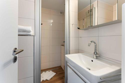 a white bathroom with a sink and a shower at Lütt Mööv in Wenningstedt