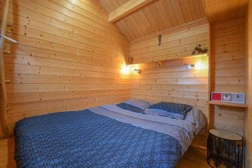a bedroom with a bed in a wooden room at Le chalet pour la nuit in Pont-Sainte-Marie