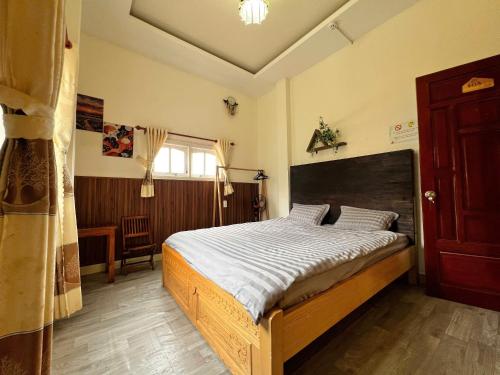 a bedroom with a large bed with a wooden headboard at TeeDalat Home in Khu Chi Lăng