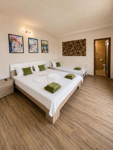 two large beds in a room with wooden floors at Vila Manila in Eforie Nord