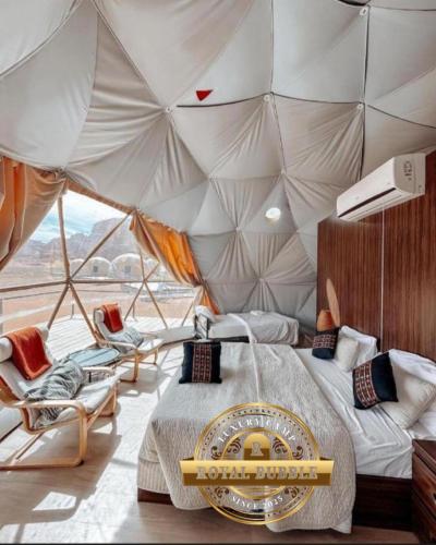 ein Zimmer mit Bett und Stühlen in einem Zelt in der Unterkunft ROYAL BUBBLE lUXURY CAMP in Wadi Rum