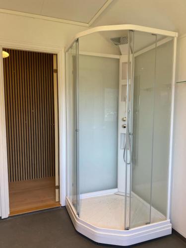 a glass shower in a room next to a door at Appartment in Jørpeland