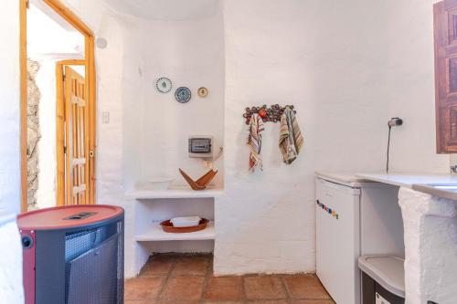 a kitchen with white walls and a counter with a refrigerator at Casa Lola - off grid vakantiehuisje - Puerto Mika in Torviscón