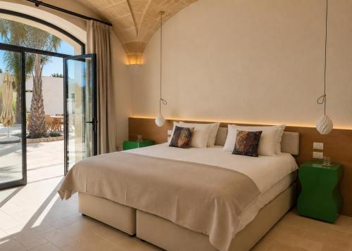 a bedroom with a large bed and a large window at Tenuta Legaro in Cozzana