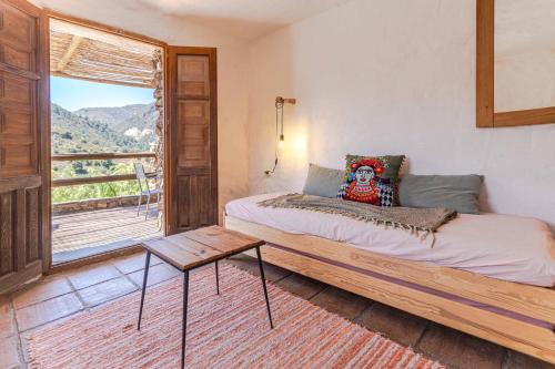 a bedroom with a bed with a table and a window at Casa Lola - off grid vakantiehuisje - Puerto Mika in Torviscón