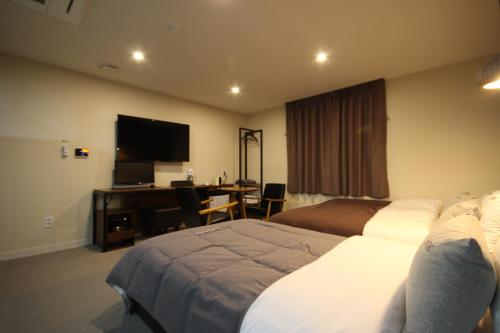 a hotel room with two beds and a desk at Busan Station Dino Hotel in Busan