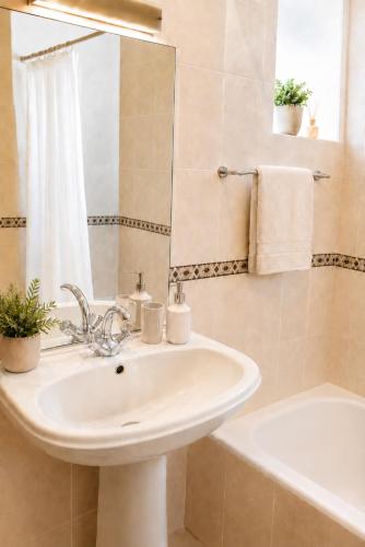 a bathroom with a sink and a mirror and a tub at 3B flat in Portimão