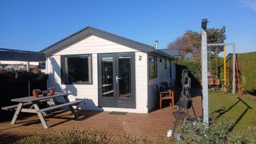 a small white shed with a picnic table and a table at Sunny Side at the Sea in Hoek van Holland