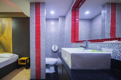 a bathroom with a sink and a toilet and red tiles at Hotel Kalifornia in Bello