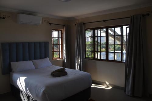 a bedroom with a bed and two windows at Sea & Forest Self Catering Estate - Durban Kingsburgh in Kingsborough