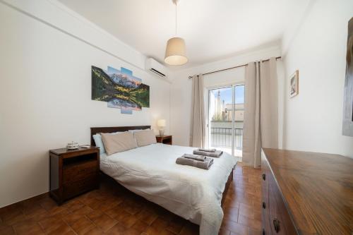 a bedroom with a bed and a large window at Casa Linda in Olhão