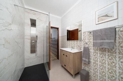 a bathroom with a shower and a sink and a mirror at Casa Linda in Olhão