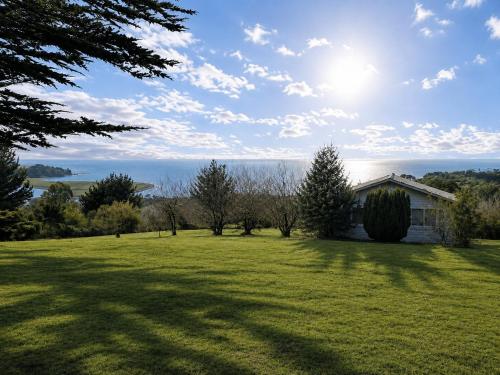 a field of green grass with a house in the background at El Urco Chiloé - Cabaña Guapilacuy in Ancud
