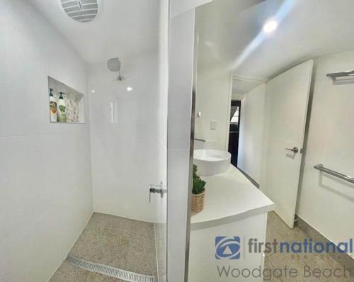 a white bathroom with a sink and a mirror at 58 The Esplanade in Woodgate