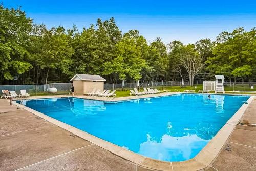 a large blue swimming pool with chairs and trees at House in the Woods in Albrightsville