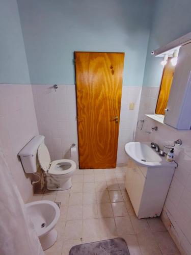 a bathroom with a toilet and a wooden door at Fy Lle -Mi lugar- Gaiman in Gaiman