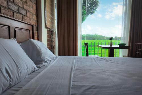 a bedroom with a white bed with a large window at Nil Nadiya Holiday Resort in Matara