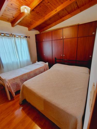 two beds in a room with wooden walls and wooden floors at Fy Lle -Mi lugar- Gaiman in Gaiman