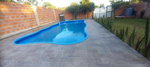 a blue pool in a backyard with a brick wall at Quinta Sinaí in Encarnación