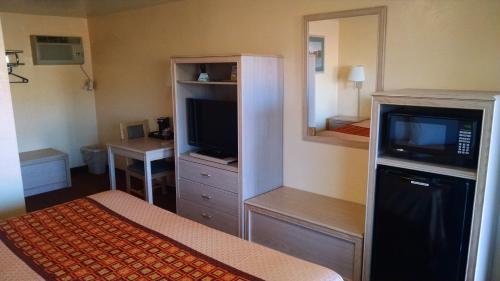 a hotel room with a bed and a tv and a bedroom at White Sands Motel in Alamogordo