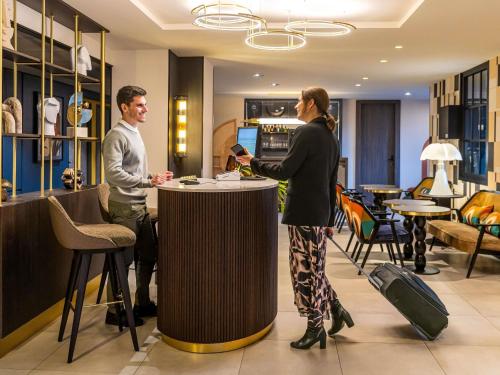 Ein Mann und eine Frau stehen an einer Bar in der Unterkunft ibis Styles Saint-Quentin in Saint-Quentin
