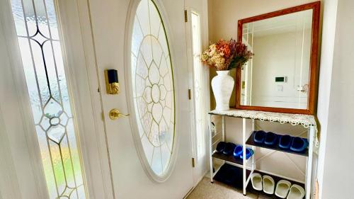 a hallway with a door and a mirror and a vase with flowers at Ocean View Home Nanaimo in Nanaimo