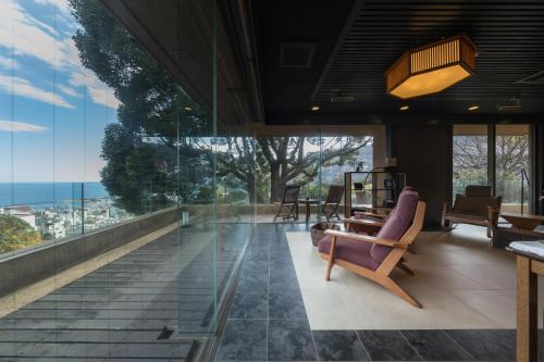a room with a balcony with a view of the ocean at Watei Kazekomichi in Atami