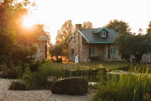 a woman in a white dress standing in front of a house at Chão do Rio - Turismo de Aldeia - Serra da Estrela in Seia