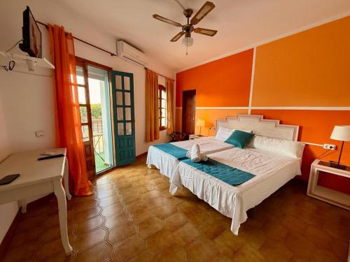 a bedroom with a bed with an orange wall at Hostal Los Arcos Vejer in Vejer de la Frontera
