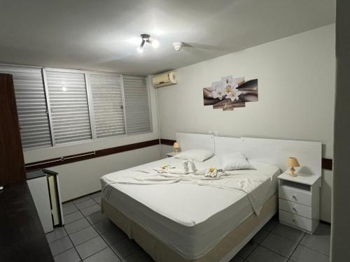 a bedroom with a white bed and a window at Pousada Fecep in Guaratuba