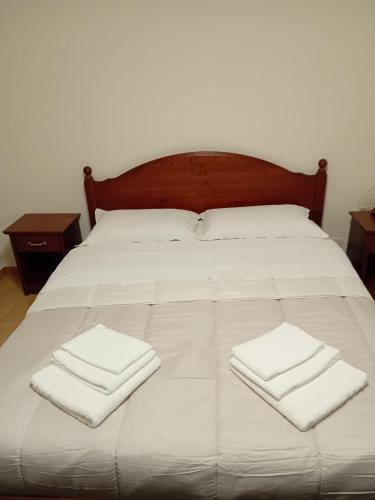 a bed with white sheets and two folded towels on it at Le vigne in Asti