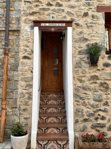 a stone building with a wooden door and stairs at Apartament Cal Barracaire in Vilallonga de Ter