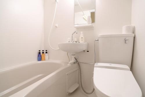 a bathroom with a white tub and a toilet and a sink at Osaka Teikoku Hotel in Osaka