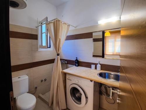 a small bathroom with a washing machine and a sink at Billy's Studio's in Karistos
