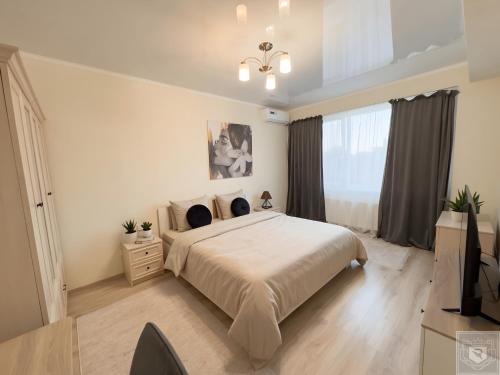a bedroom with a large bed and a television at RentHouse Apartments Cozy Stay in Chişinău