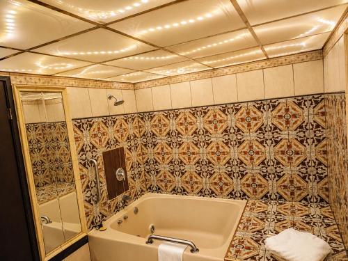 a bathroom with a tub and a tiled wall at Chateau Royale Inn in Lake Geneva