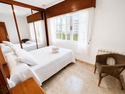 a bedroom with a bed and a chair and a window at Airtegal Casa da Praia Cedeira in Cedeira