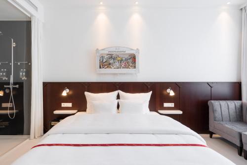 ein Schlafzimmer mit einem großen weißen Bett und einem Stuhl in der Unterkunft Ruby Leni Hotel Dusseldorf by IHG in Düsseldorf